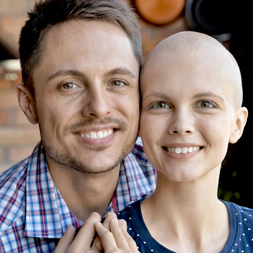 A man smiles next to a smiling woman with a shaved head following her chemotherapy treatment