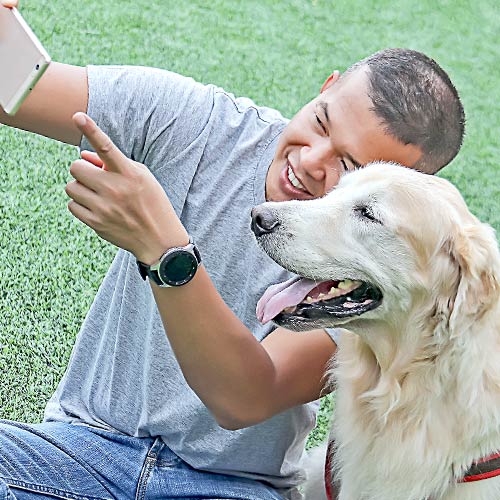 A man in a gray shirt takes a selfie with his golden retriever following successful chemotherapy treatment.