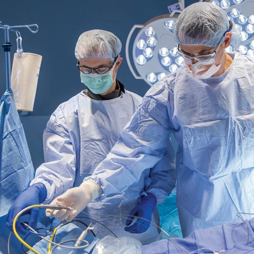 Two surgeons in full scrubs perform a surgery in the operating room.