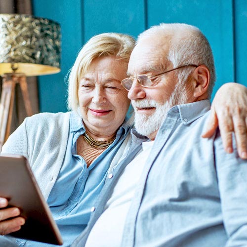 An older man and woman complete an eVisit on their tablet device in the comfort of their own home
