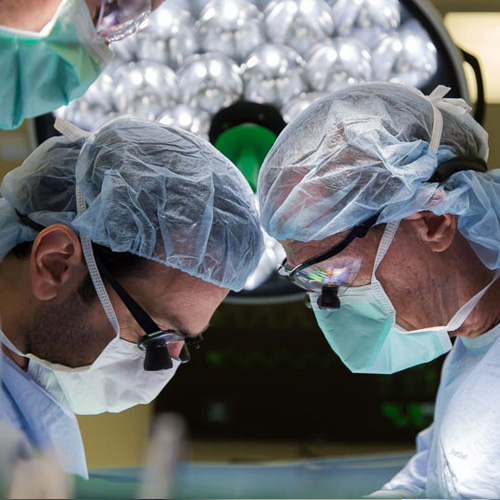 Two surgeons in blue scrubs perform a heart procedure in the operating room