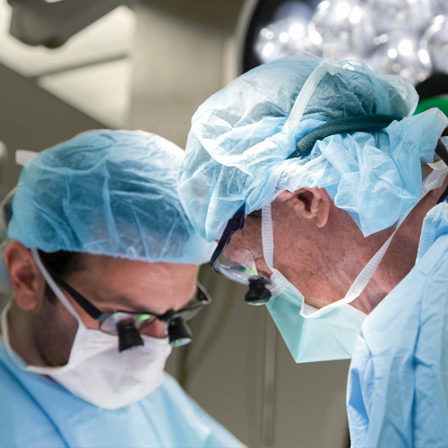 Two heart surgeons in scrubs perform a heart operation in the OR